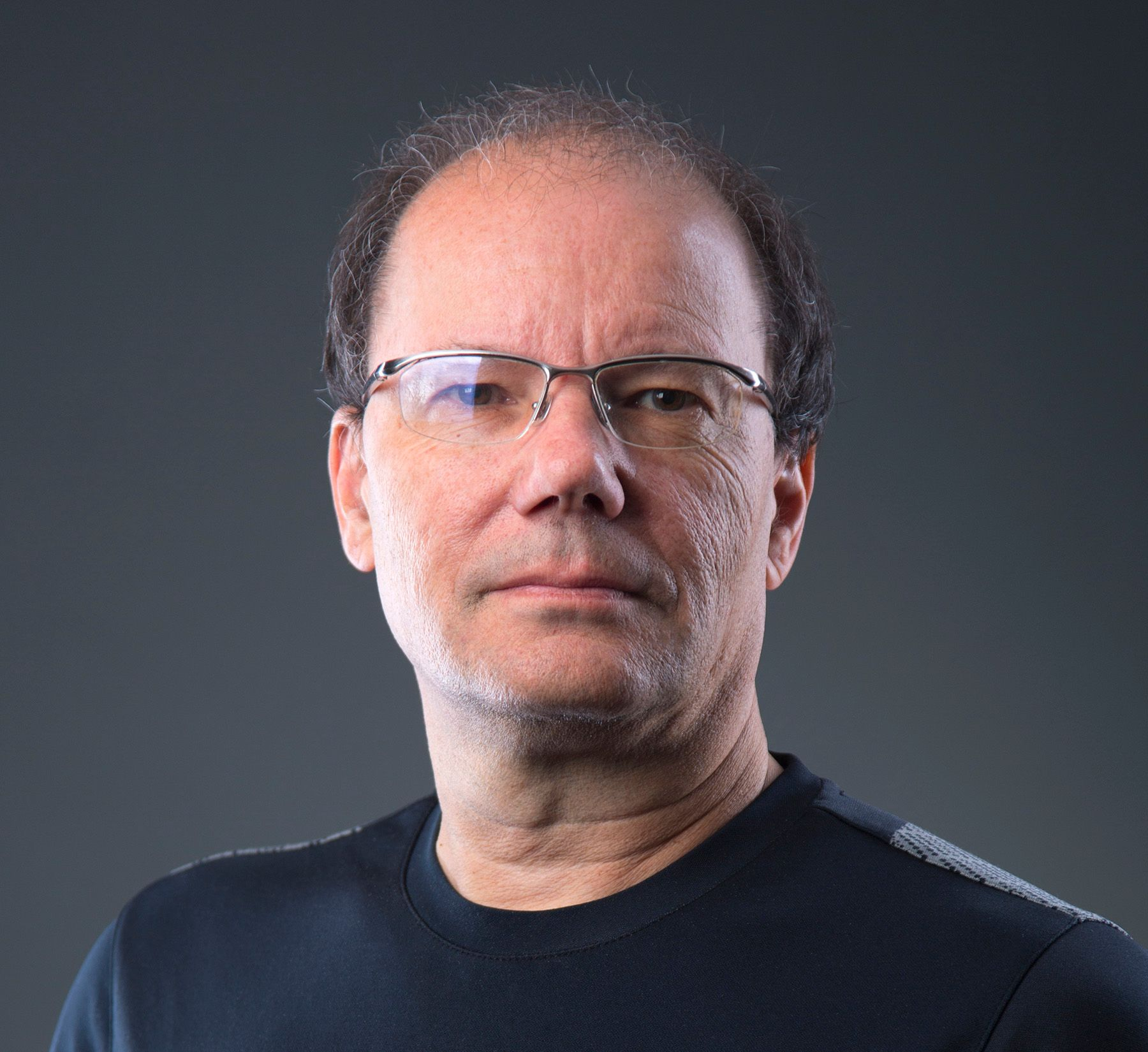 Man with glasses, gray background.