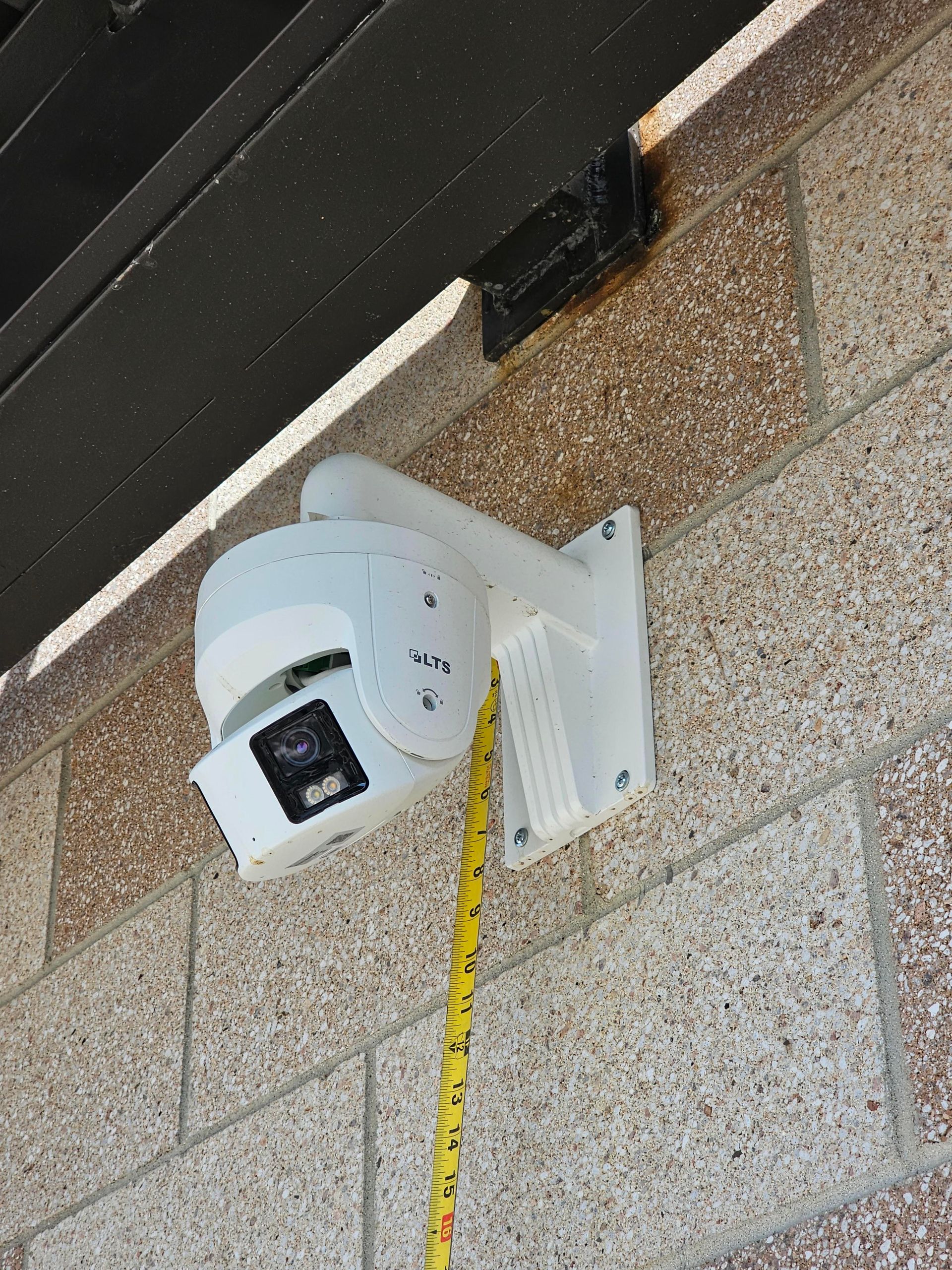 A cluttered workshop interior with cabinets, tools, and a security camera mounted overhead.