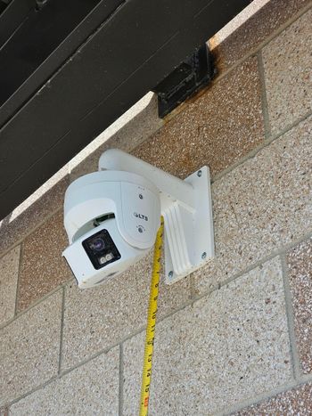 A cluttered workshop interior with cabinets, tools, and a security camera mounted overhead.