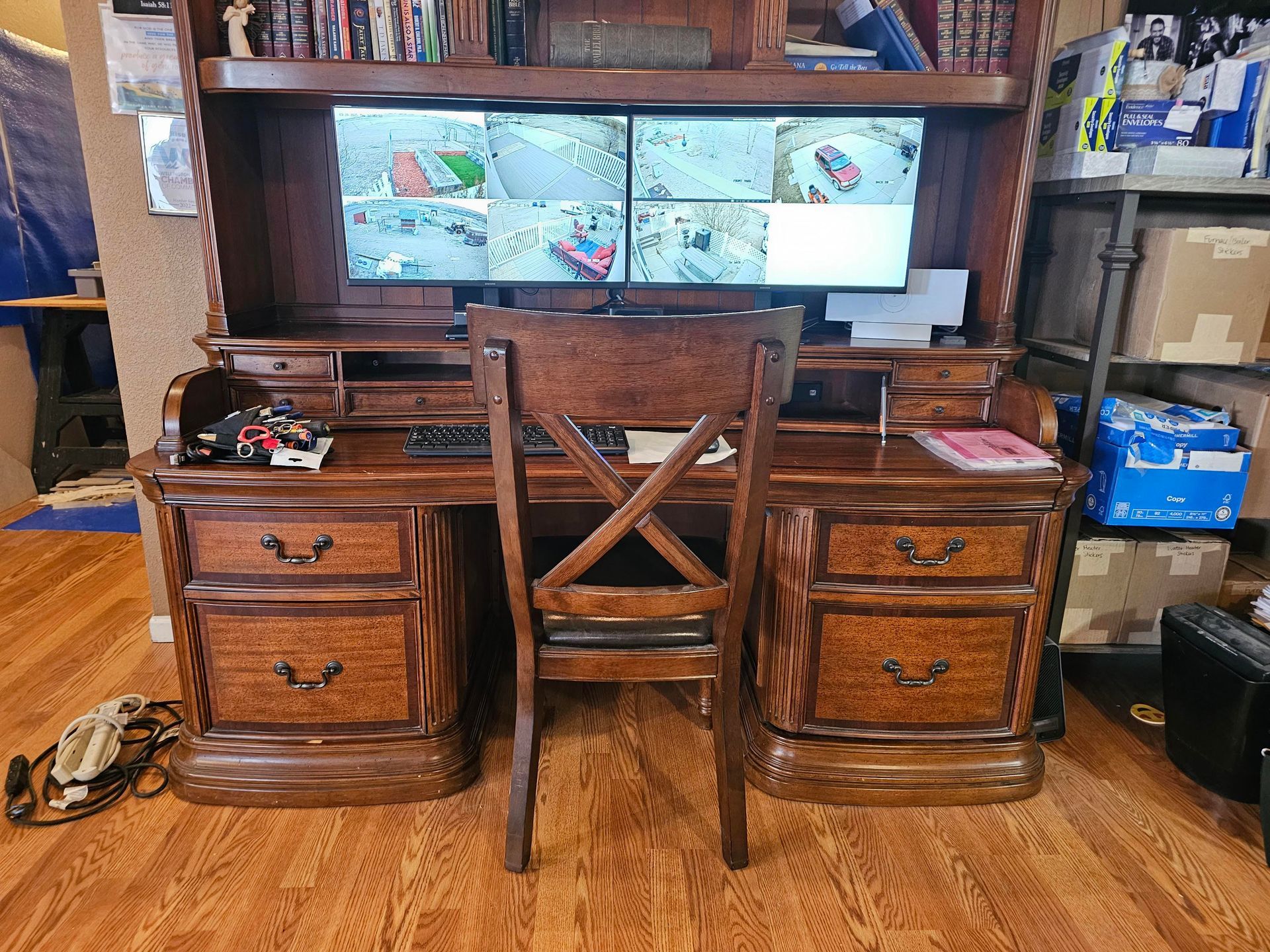 Smoke detector mounted on a white ceiling, overlooking a modern living room with light furniture and bookshelves.