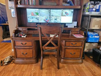 Smoke detector mounted on a white ceiling, overlooking a modern living room with light furniture and bookshelves.