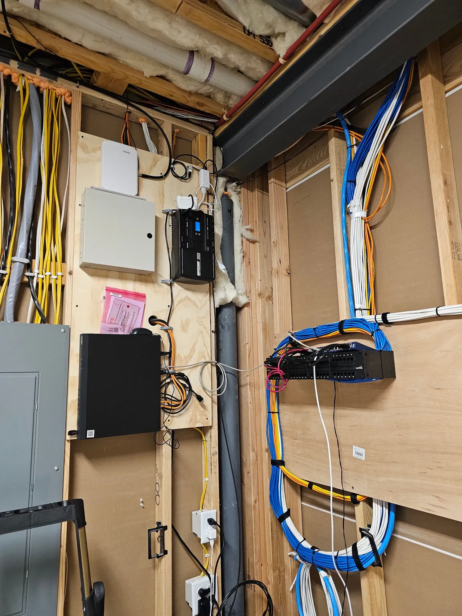 Electrical wiring and boxes mounted on wooden studs in a utility room.