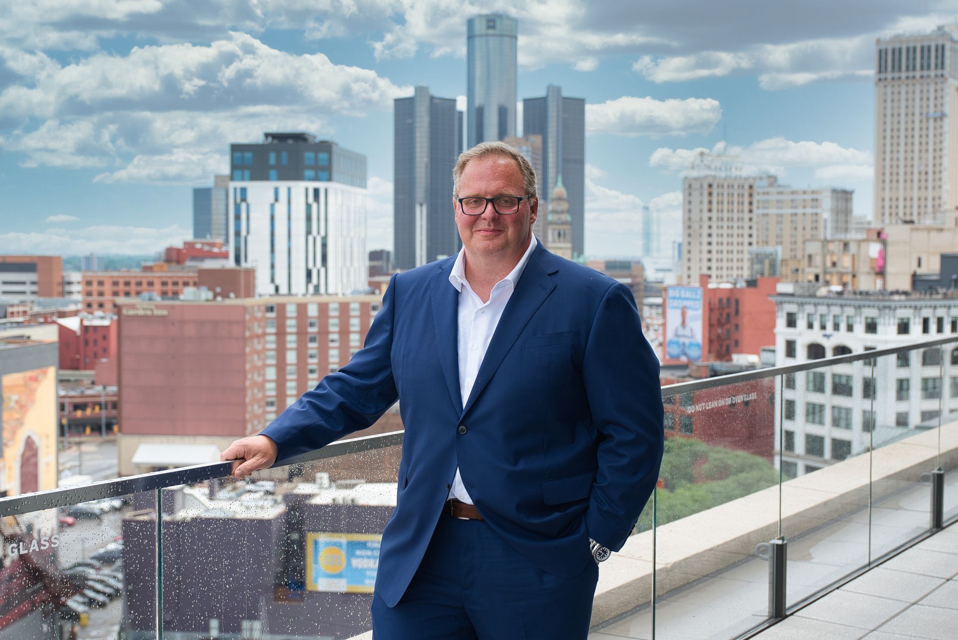 A man in a suit and white shirt is sitting in front of a black background.