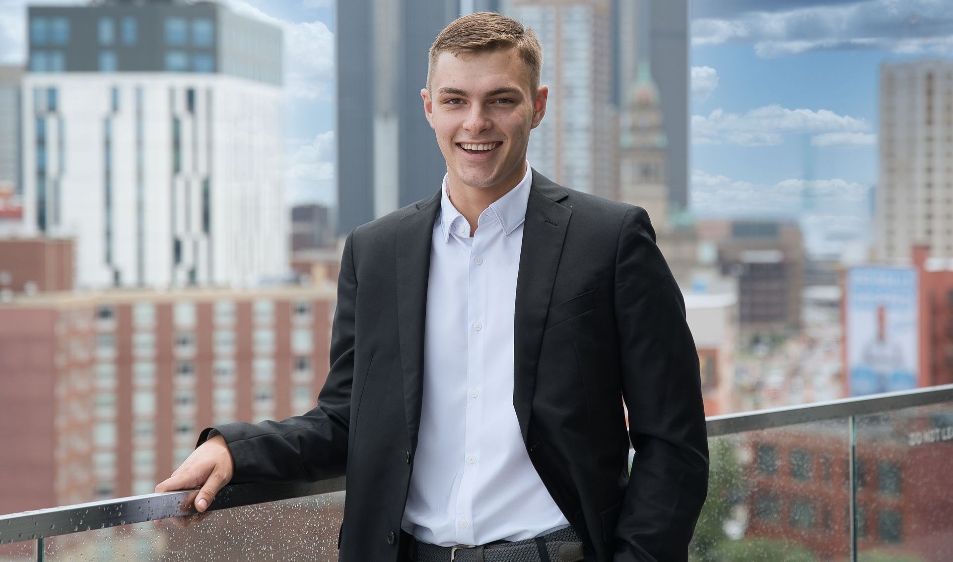 A man in a suit is smiling with his arms crossed.