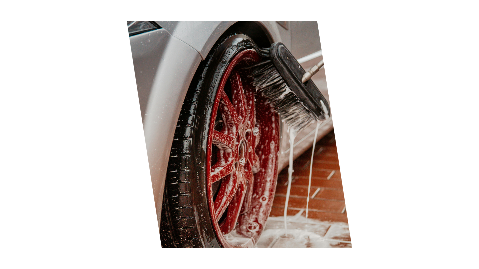 A close up of a car wheel being washed with soap.