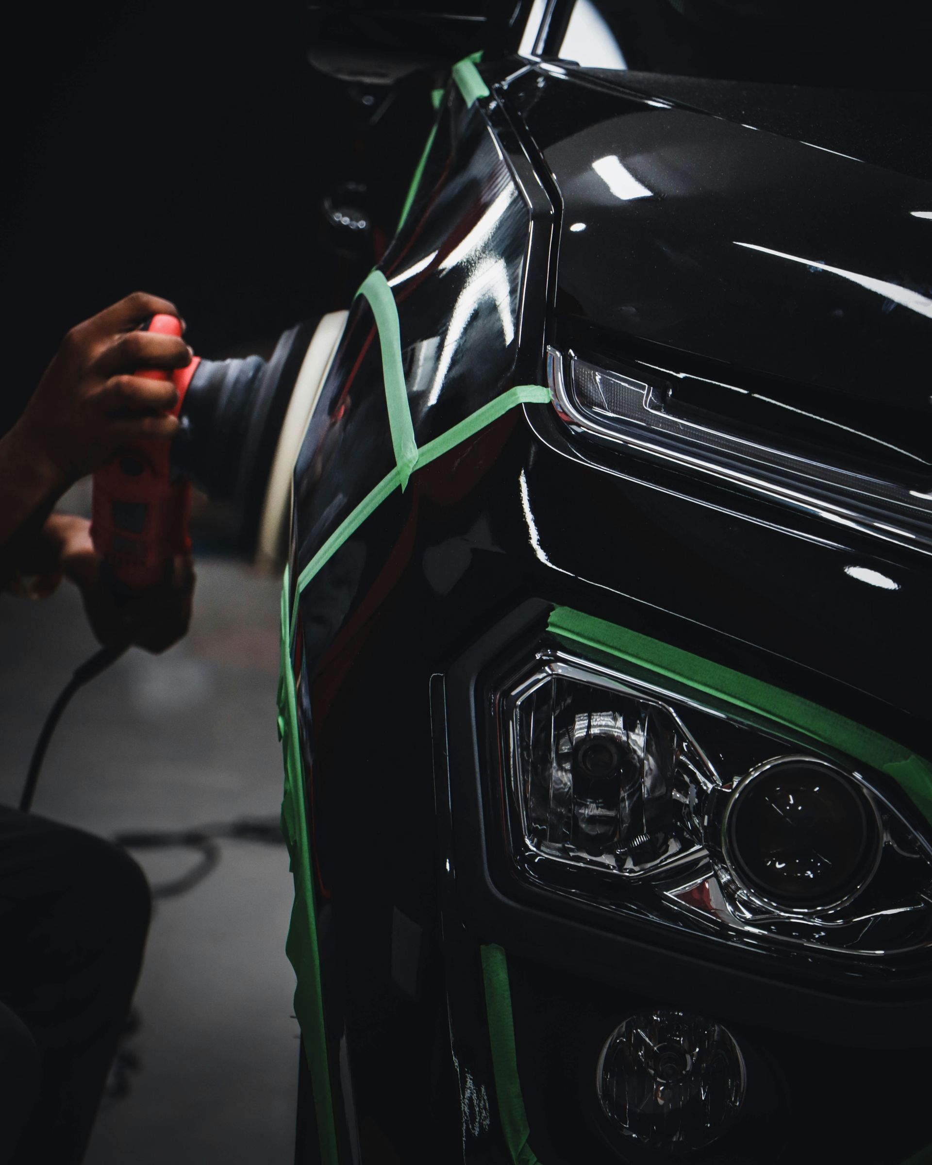 A person is polishing the front of a black car