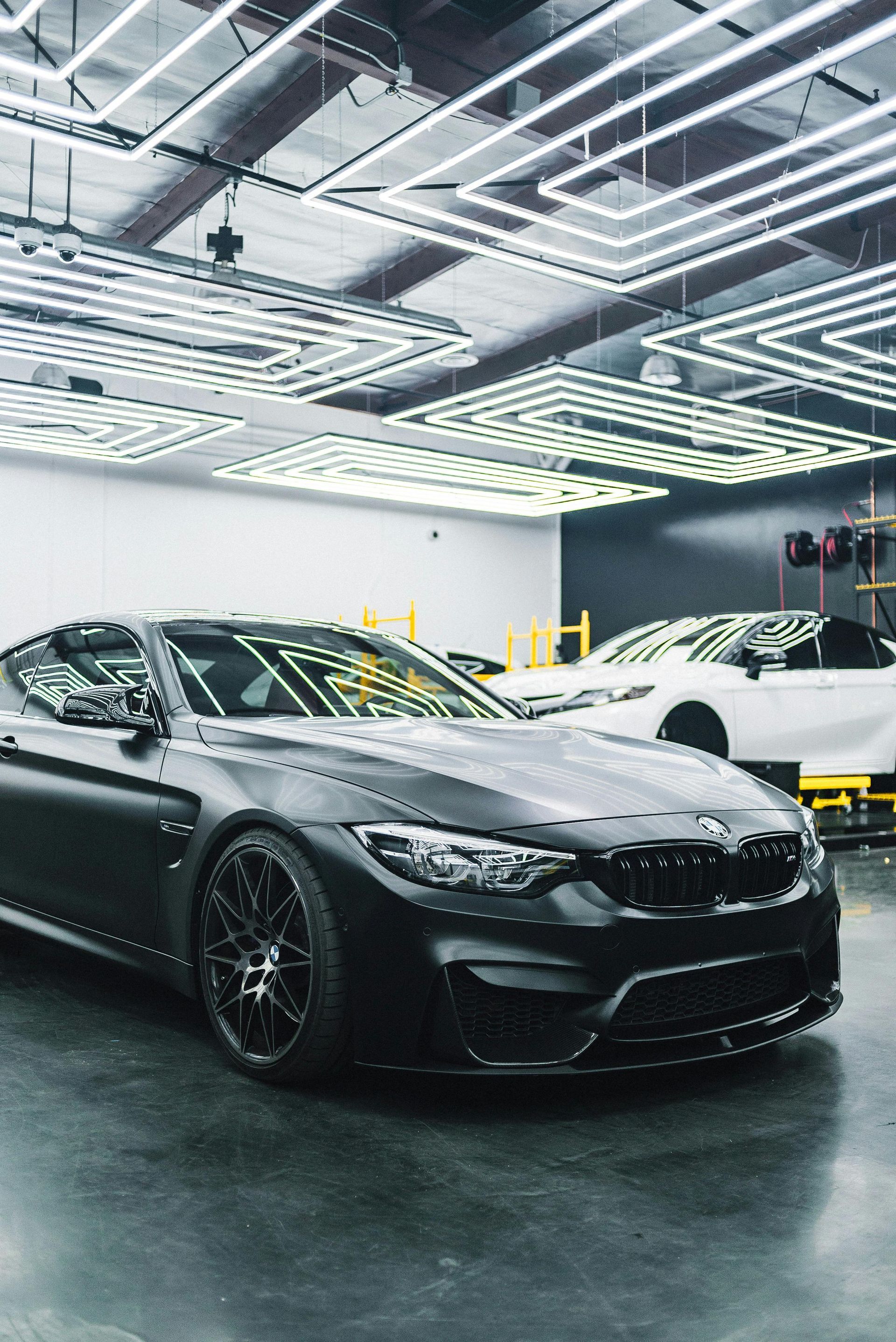A black car is parked in a garage next to a white car.