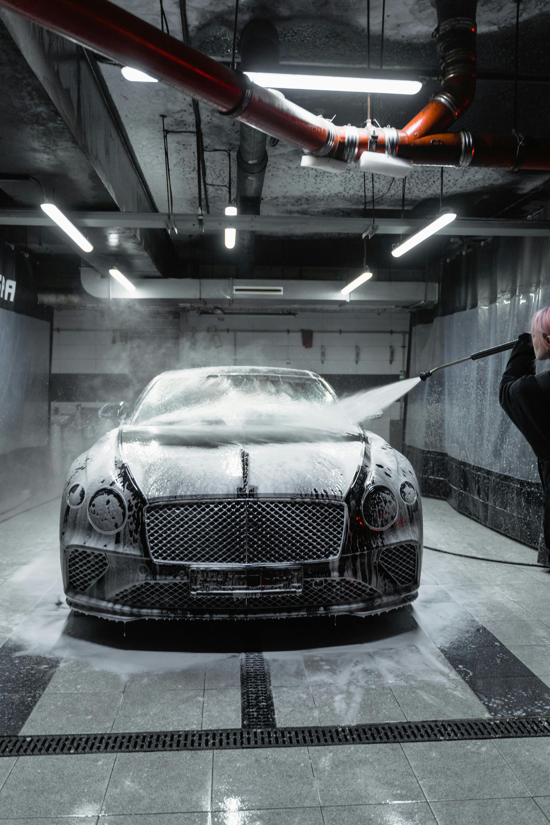 A bentley is being washed in a car wash.