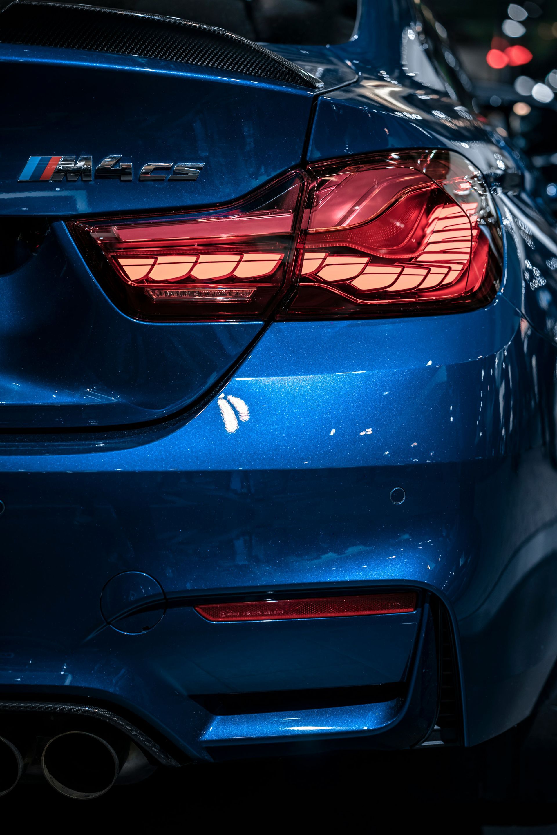 The back end of a blue bmw m4 is shown in a close up.