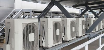 A row of air conditioners hanging from the side of a building.