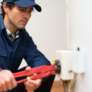 A man is fixing a toilet with a wrench.