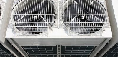 A close up of two air conditioner fans on top of a building.