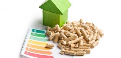 A green house is sitting next to a pile of wood pellets.