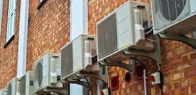 A row of air conditioners mounted on the side of a brick building.