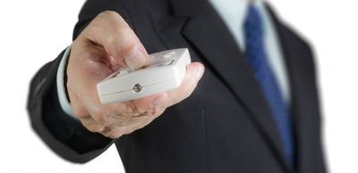 A man in a suit and tie is holding a remote control in his hand.