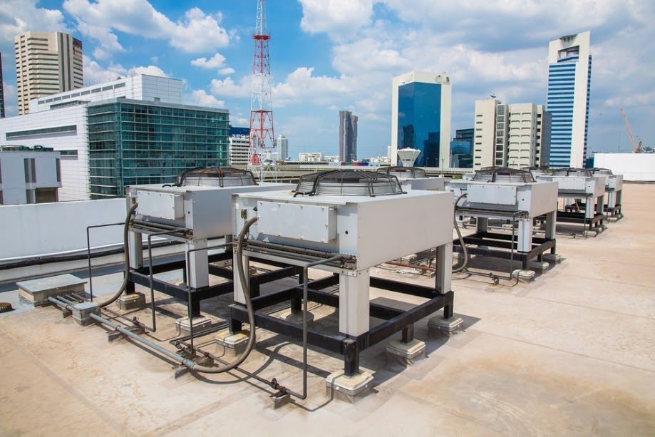 A rooftop with a lot of machinery on it and a city in the background.