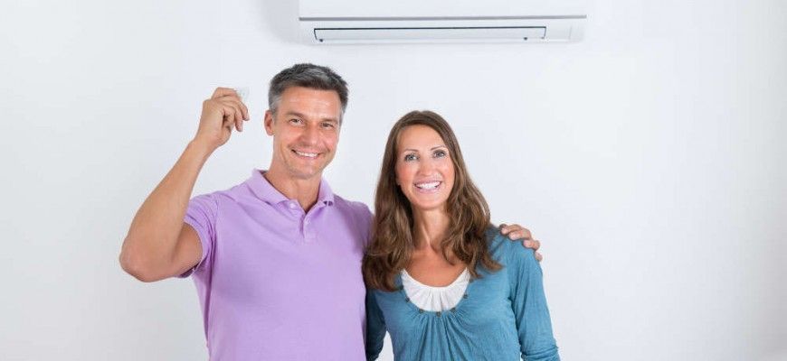 A man and a woman are standing next to each other in front of an air conditioner.