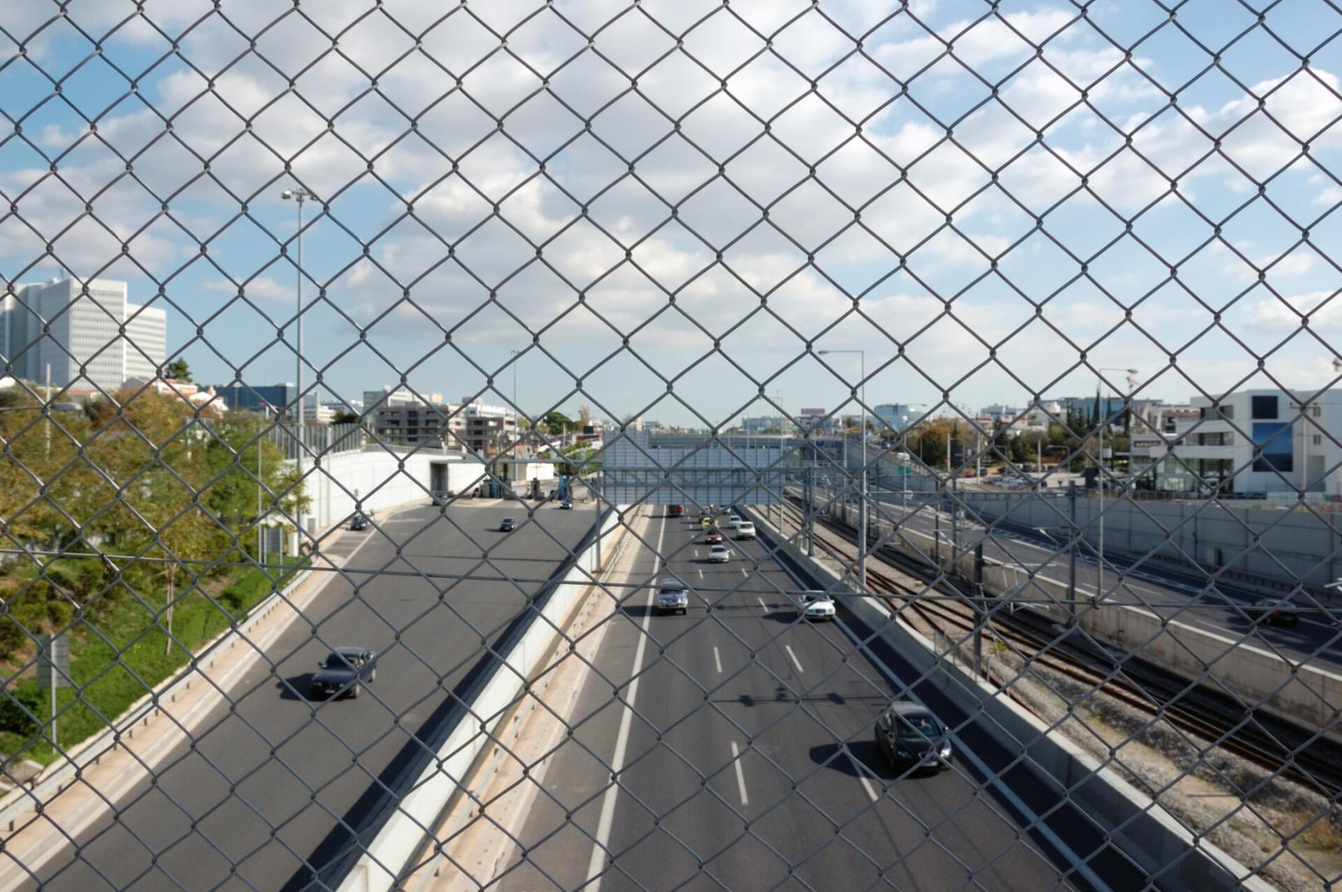 Chain Link fence installed on a pedestrian bridge over an interstate.