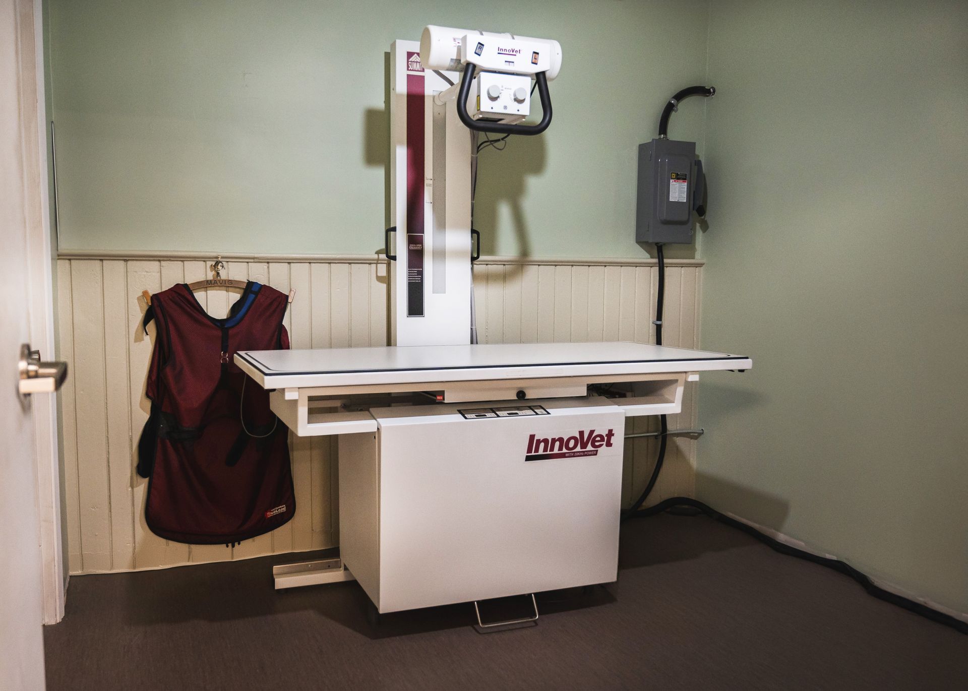 An x-ray machine is sitting in a room next to a door.