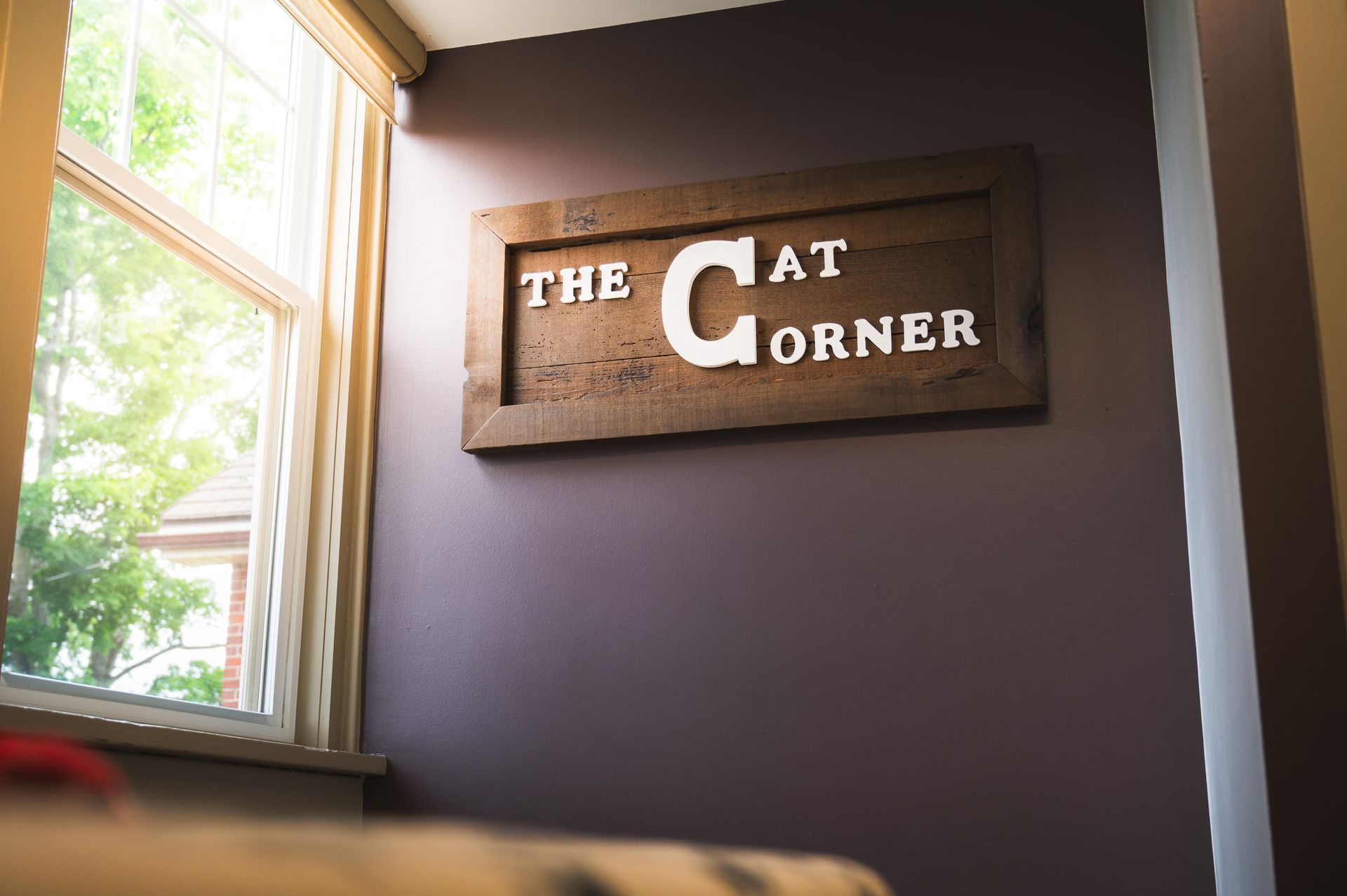 A wooden sign on a wall that says the cat corner