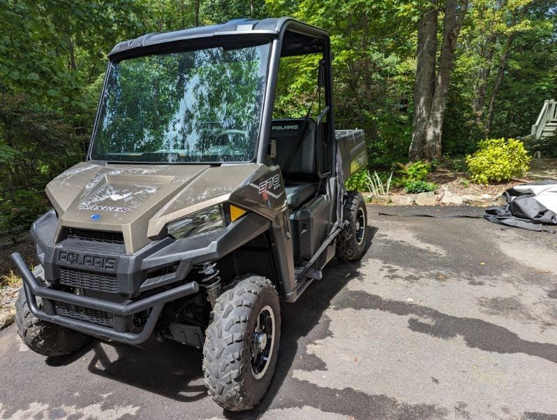 A polaris utility vehicle is parked in a driveway.