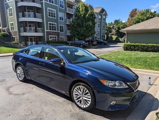 A blue car is parked in a parking lot in front of a building.