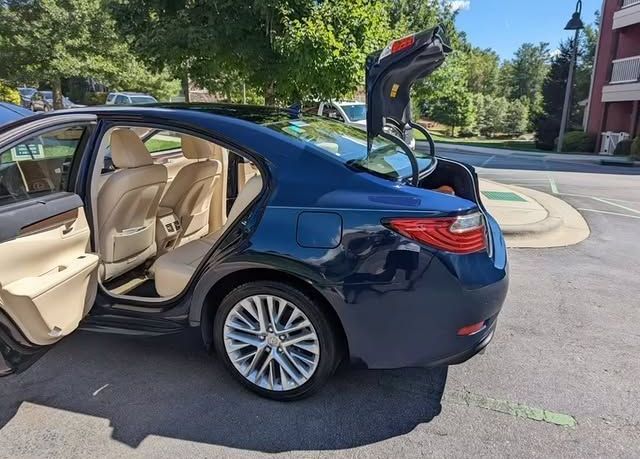 A blue car with the trunk open is parked in a parking lot.