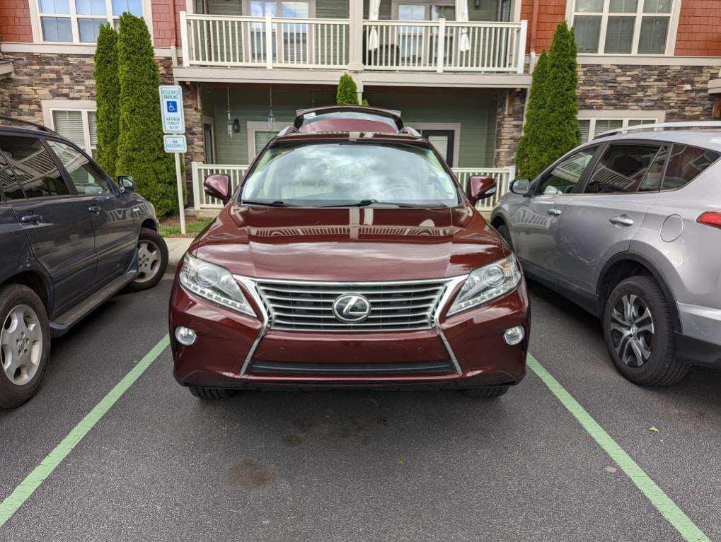 A red lexus is parked in a handicapped parking spot.