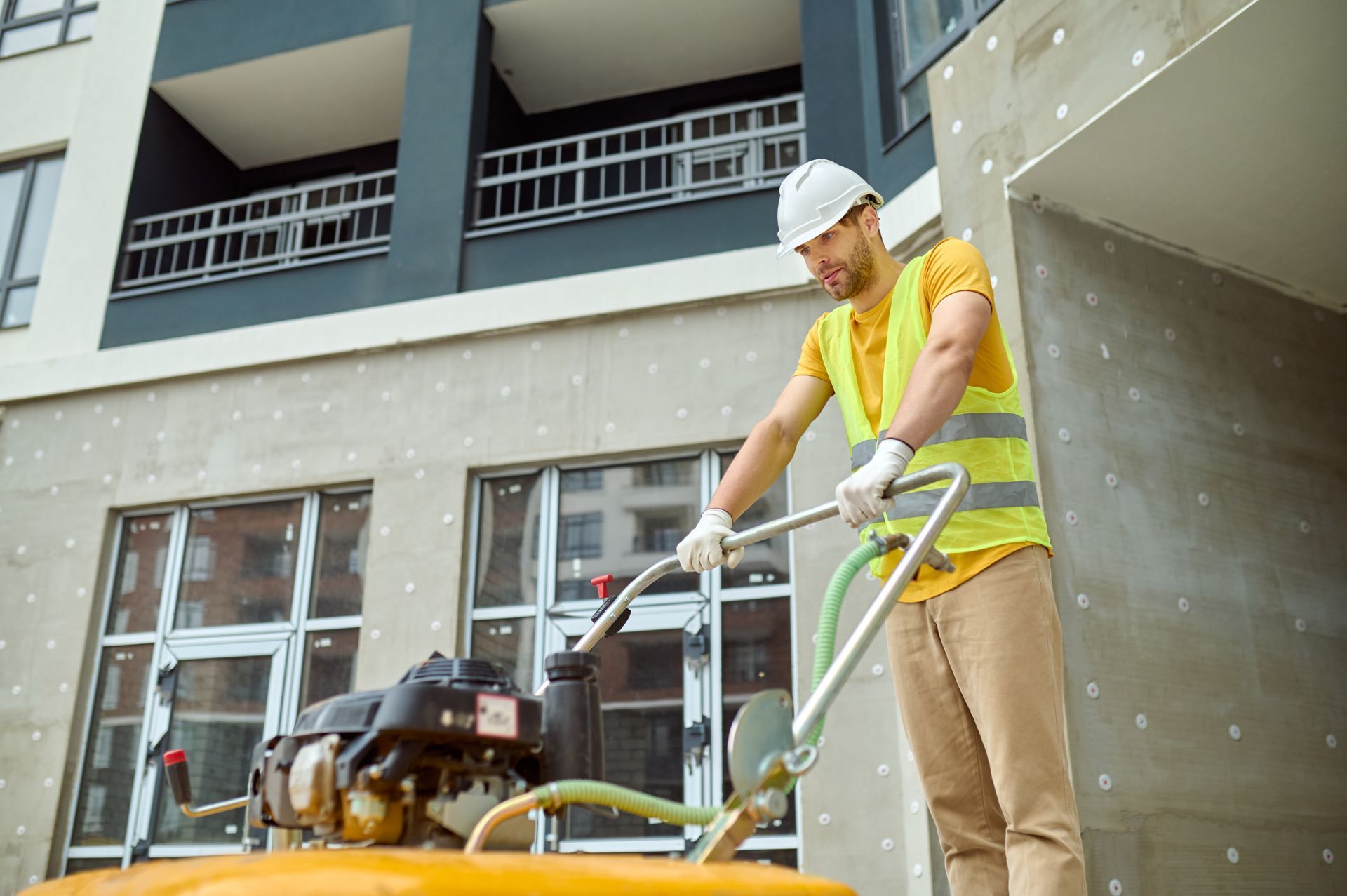 A construction worker is using a machine on a construction site.