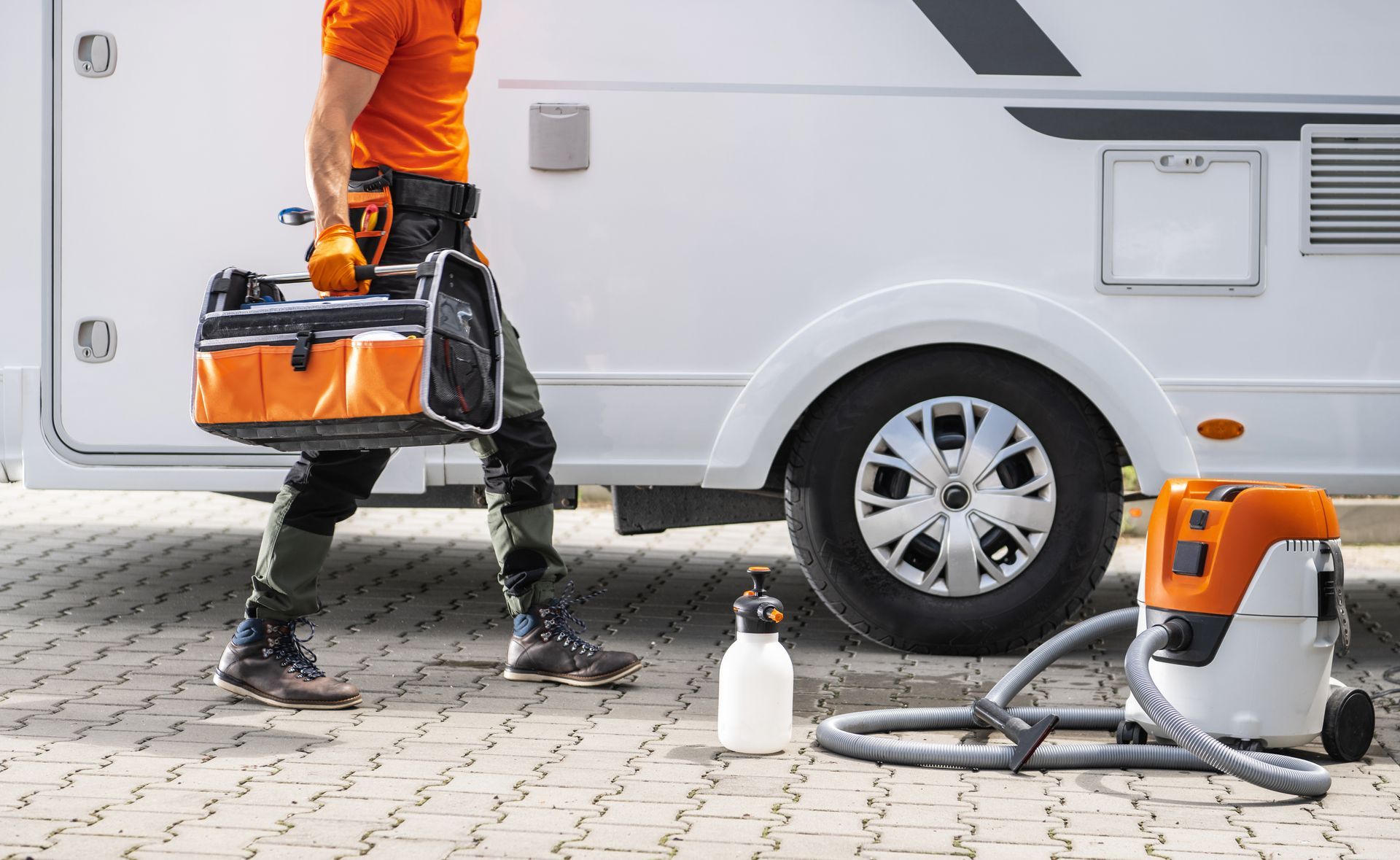 A man is carrying a toolbox next to a camper van.