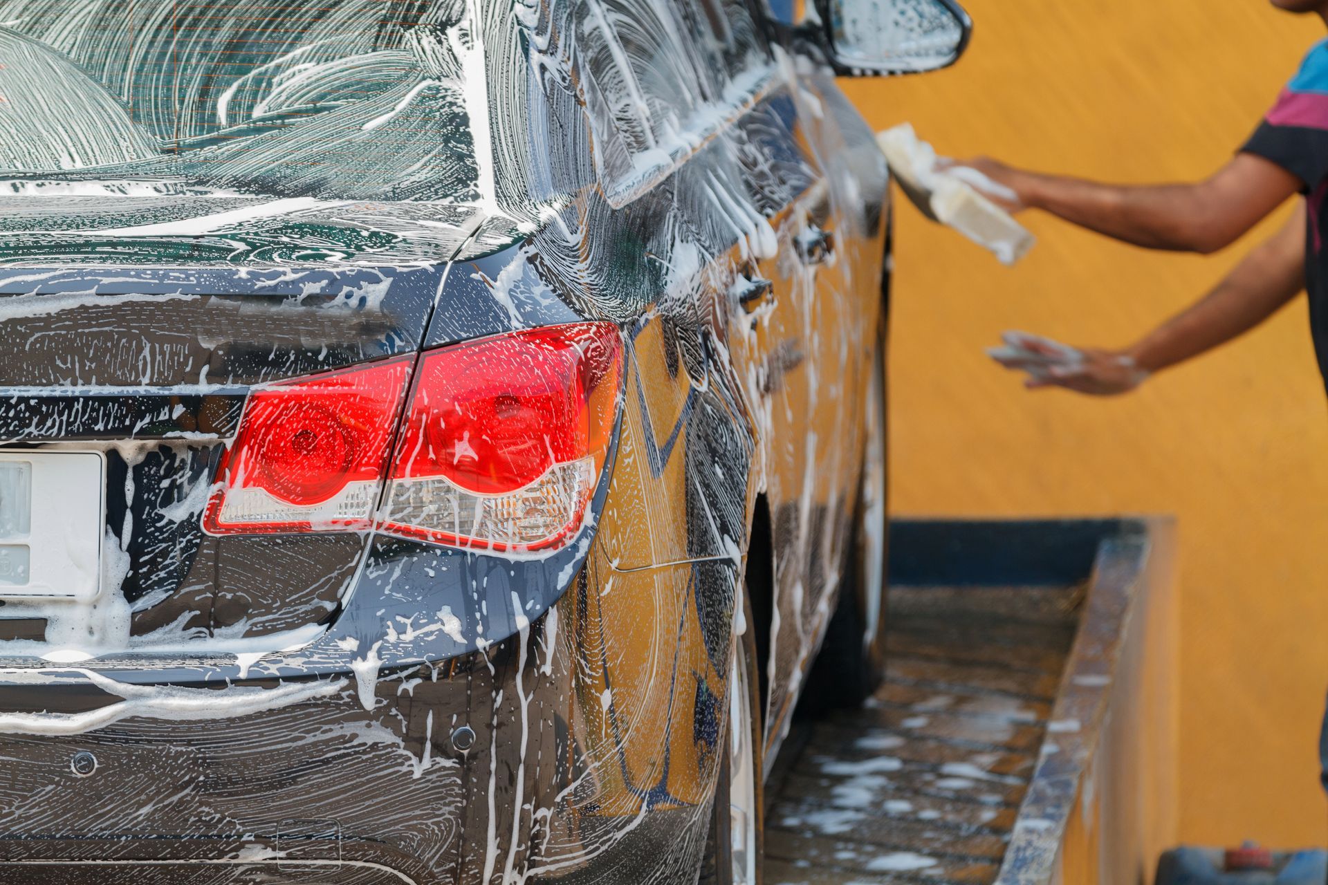 A man is washing a car in a car wash.