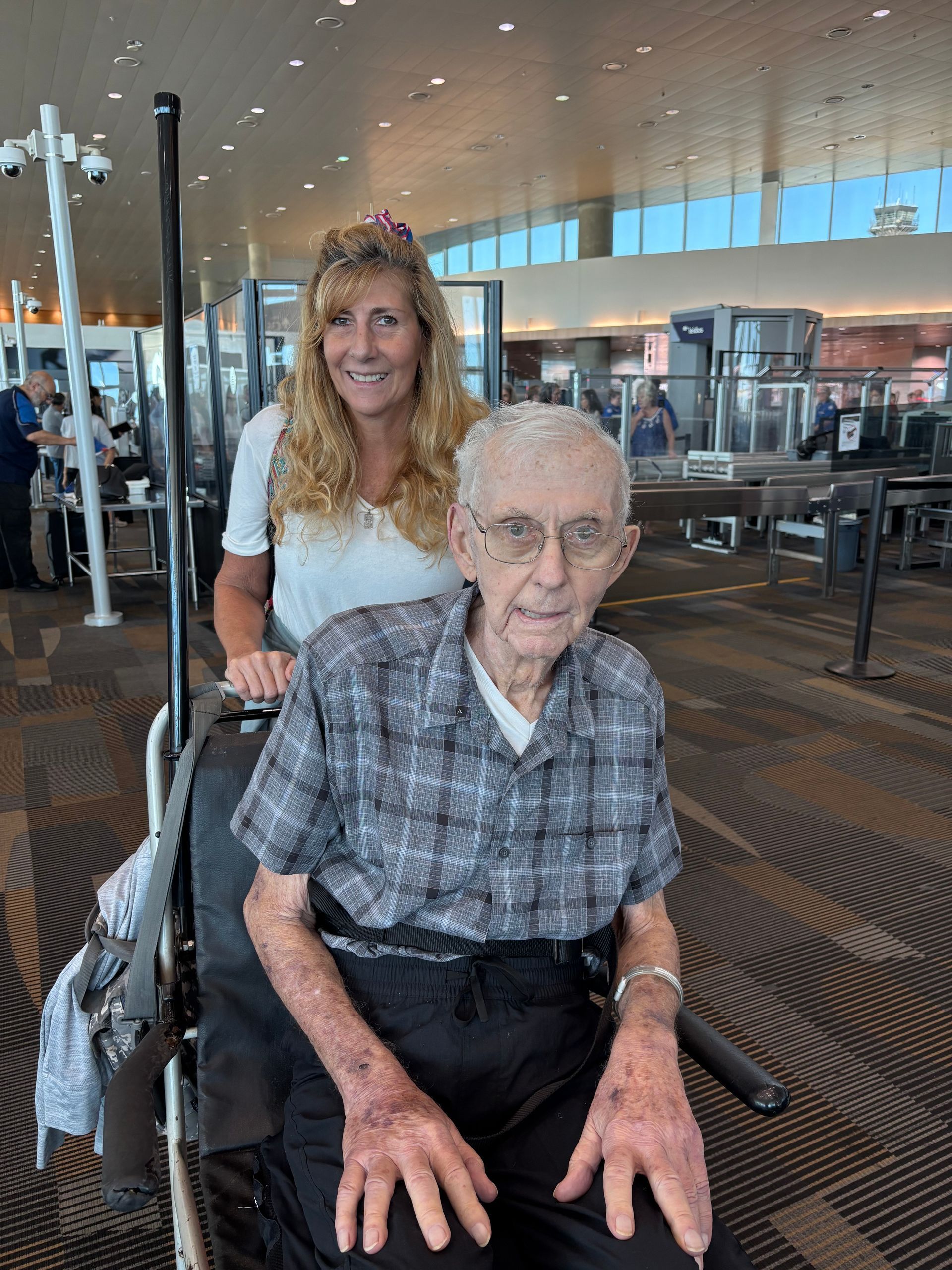 An elderly man in a wheelchair is sitting next to a woman.