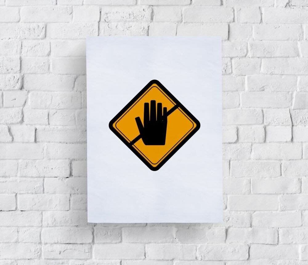 A white brick wall with a yellow sign that says no hand