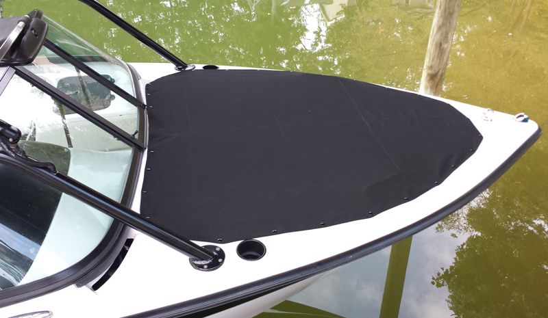 Black boat cover on a white boat in the water, docked next to a wooden pole.