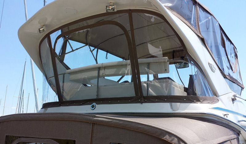 Boat cabin with clear vinyl windows, brown trim, and a blue sky in the background.