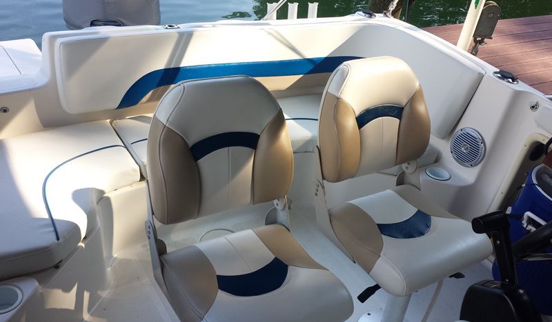 Boat interior with tan and blue seats, white walls, and a view of the water.