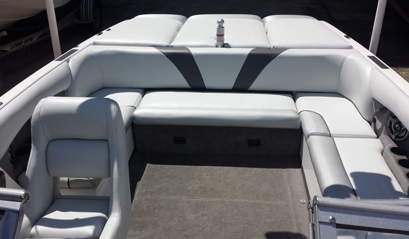 Interior of a boat with white and gray upholstery, showing seating and a central area.