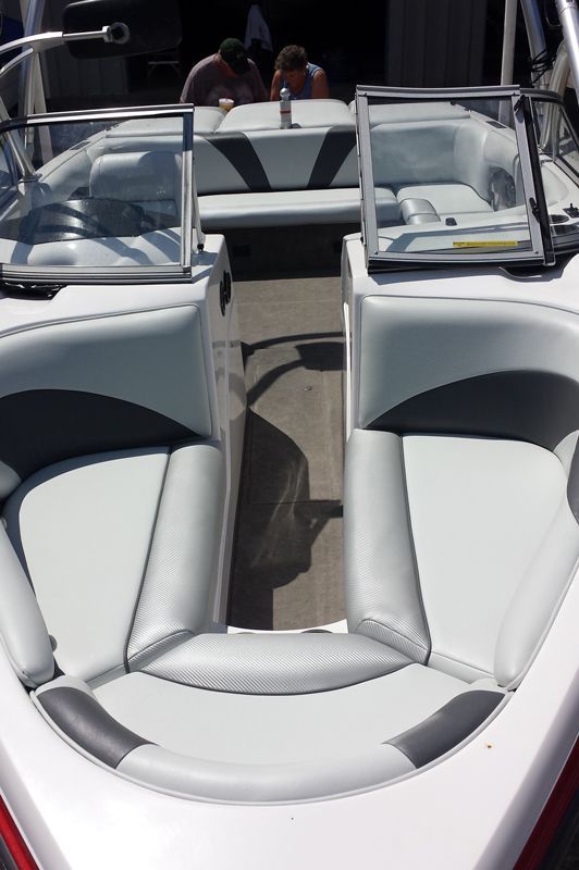 A white and gray boat interior with seating, windshields, and two people visible in the background.