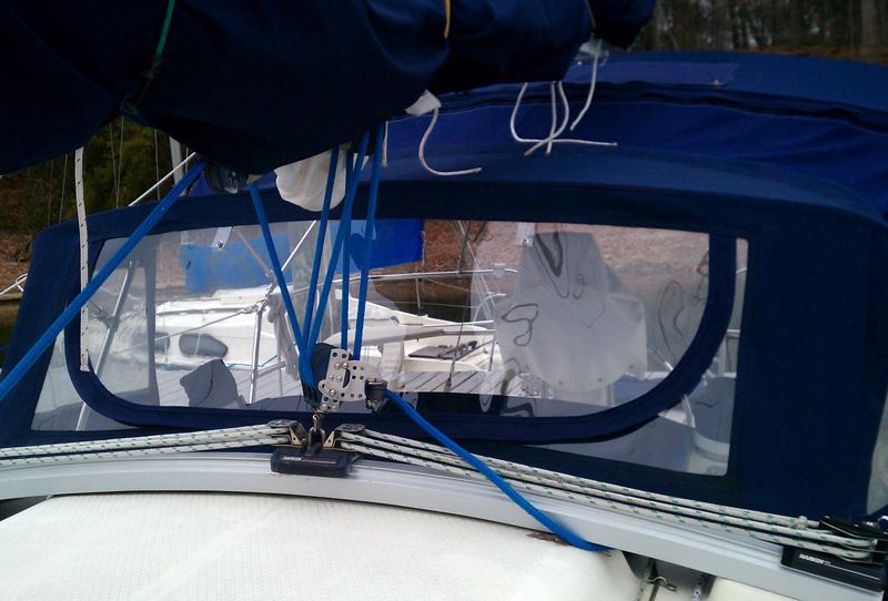 Close-up of a sailboat's navy blue dodger with clear vinyl windows; blue ropes and lines are visible.