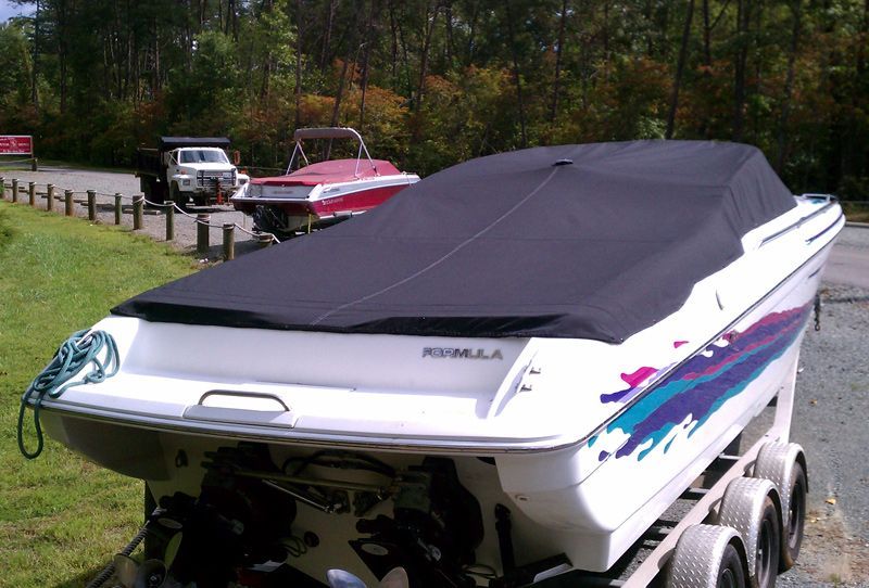 White Formula boat on a trailer, covered with a black tarp, with colorful side decals.
