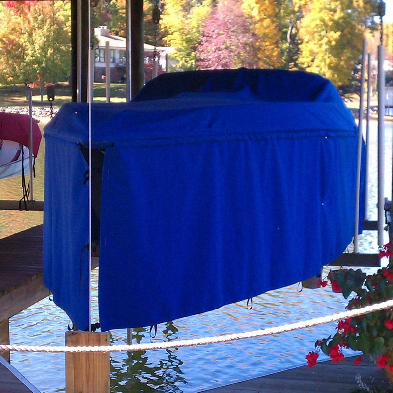 Blue boat lift cover on a dock over water with autumn trees in the background.
