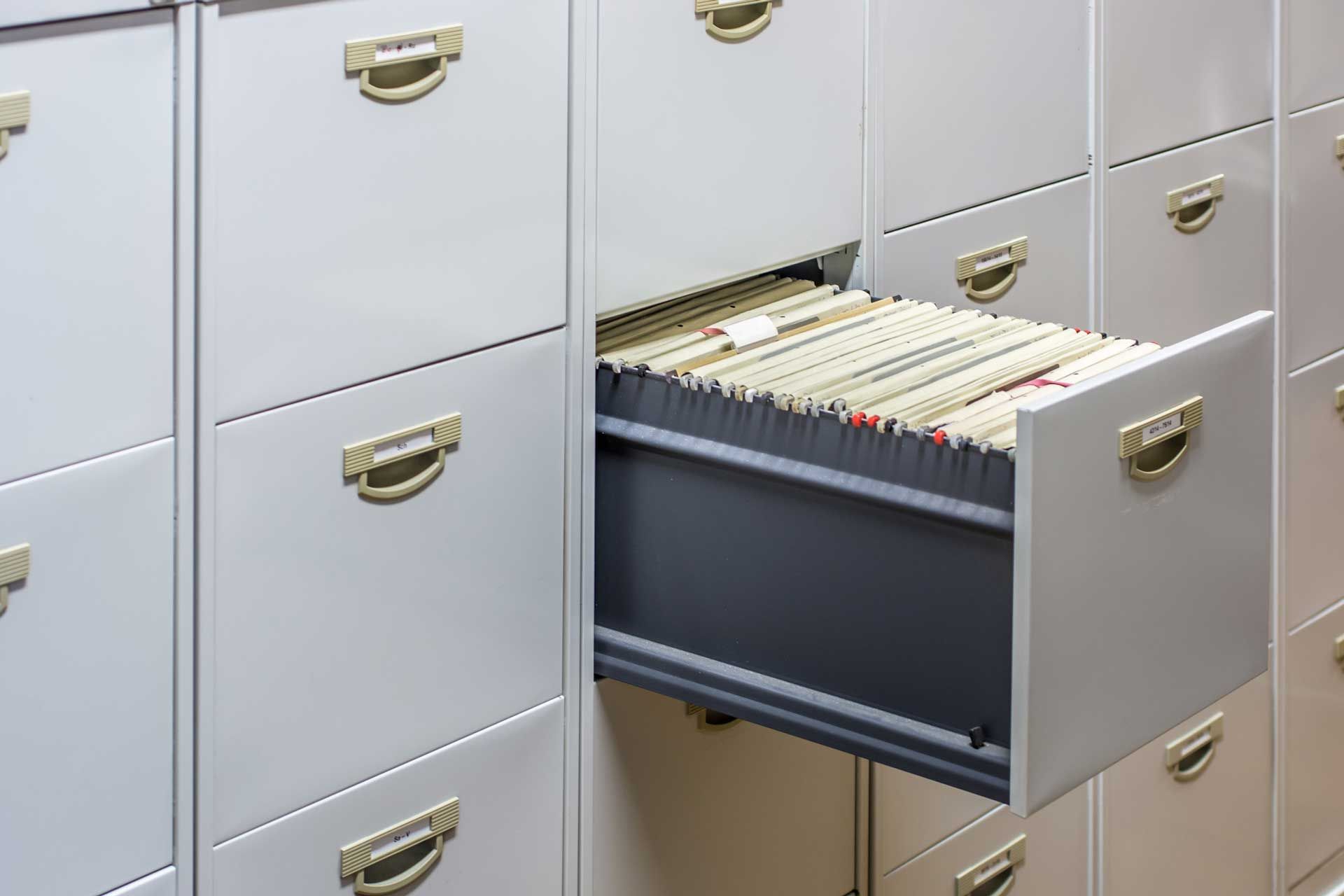 A filing cabinet with a drawer open filled with papers.