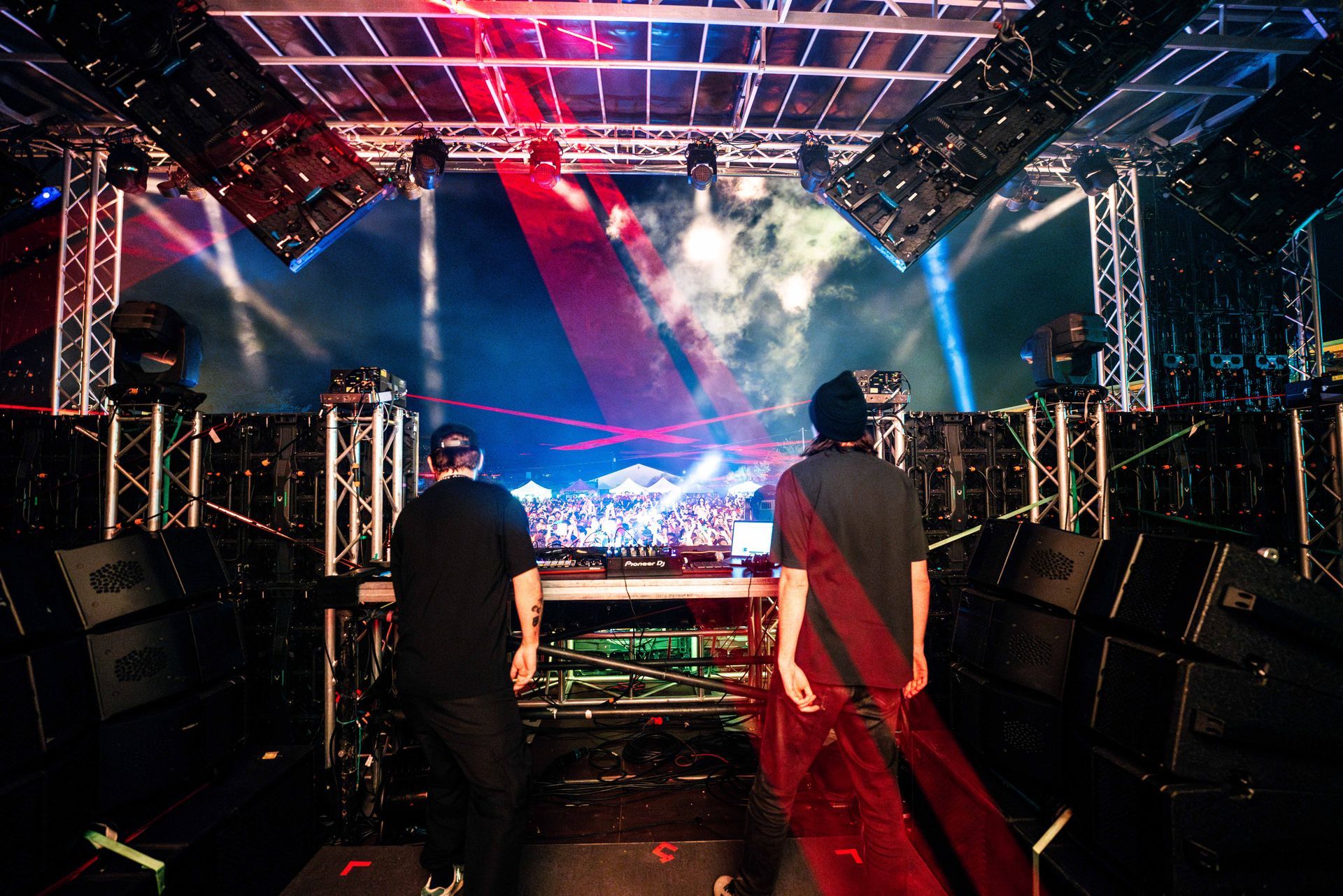 two men standing in front of a stage with a pioneer mixer