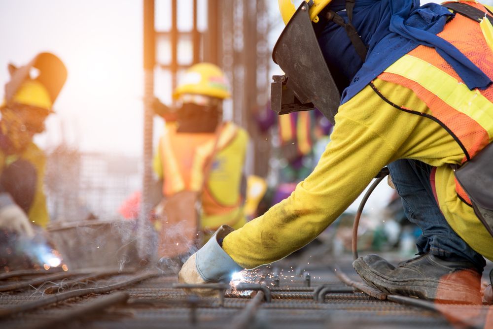 Construction Workers Welding Metal on a Construction Site, Wearing Protective Gear in Sunlight — EB Metalworks in Somersby, NSW