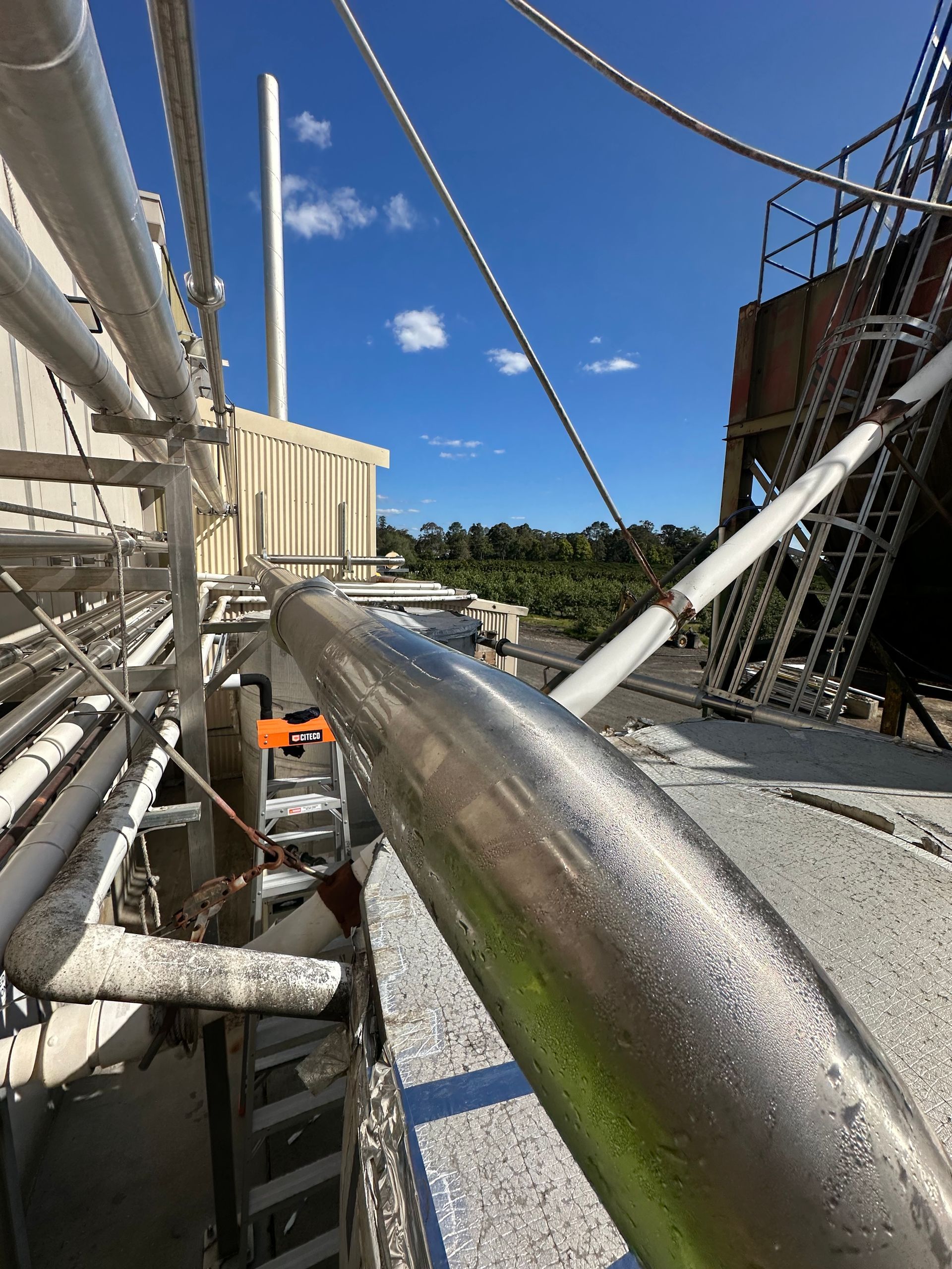 Metal pipes and scaffolding on an industrial rooftop under a blue sky — EB Metalworks in Somersby, NSW