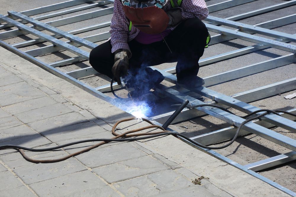 Person Welding Metal Frame Outdoors, Generating Sparks and Blue Light — EB Metalworks in Somersby, NSW