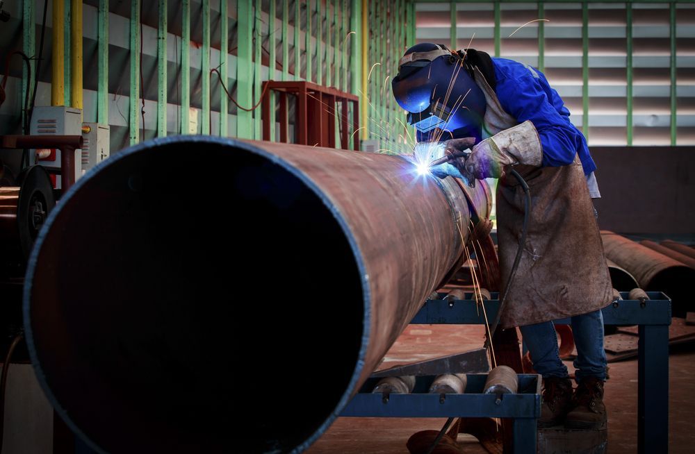 Welder Wearing Protective Gear, Welding a Large Metal Pipe in a Workshop — EB Metalworks in Somersby, NSW