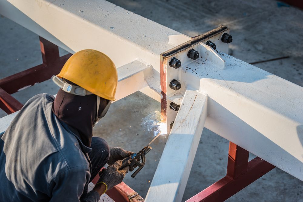 Welder in Yellow Hard Hat, Welding Metal Beams at Construction Site — EB Metalworks in Somersby, NSW