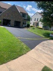 A house with a lush green lawn and a paved driveway in front of it.