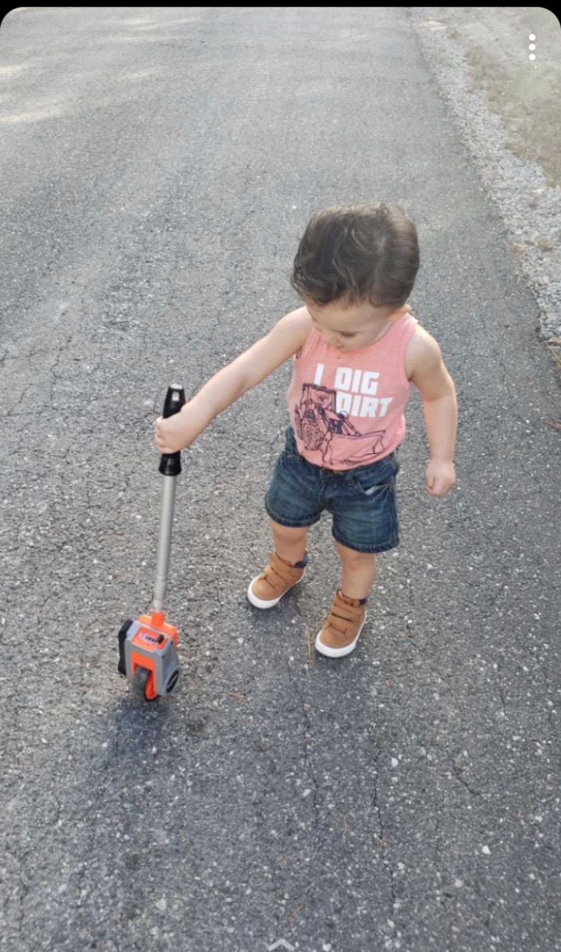 A little boy is walking down the street holding a toy.